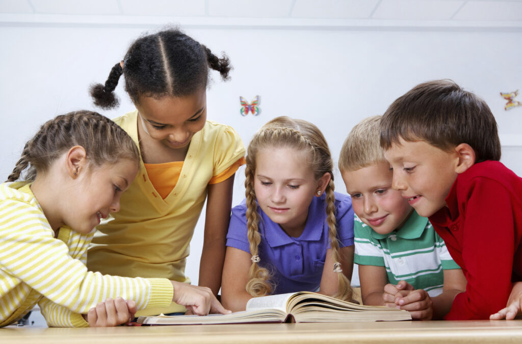 Five young children reading a book together