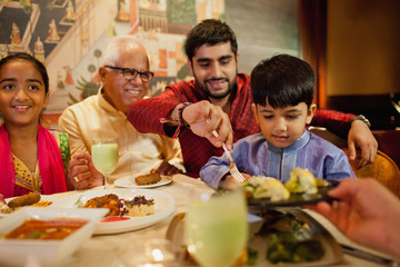 Grandfather, dad, elementary aged daughter and son eating dinner