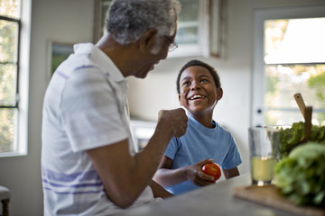 black grandfather laughing with elementary aged child at dinner table