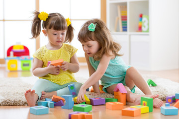 Two toddler aged girls playing with blocks together