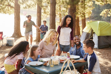 Two families eating on a table at a campsite