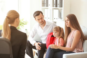 Mom and dad with elementary aged daughter talking with adult female