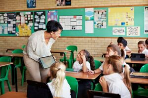 School children in uniforms in class with tablets