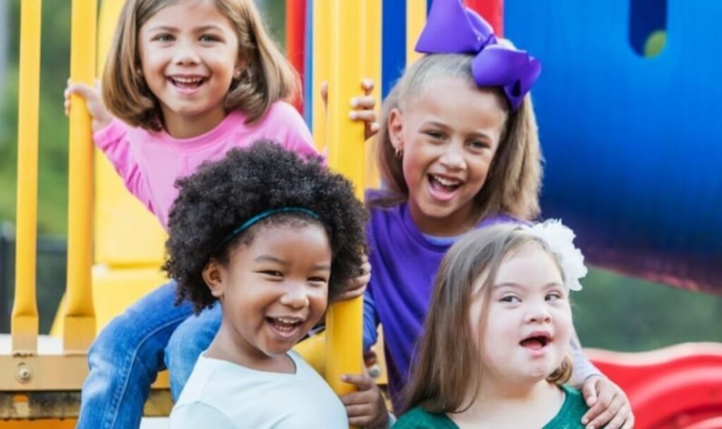 Group of four little girls smiling on the playground. 