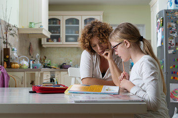 Parent and child at kitchen table doing homework