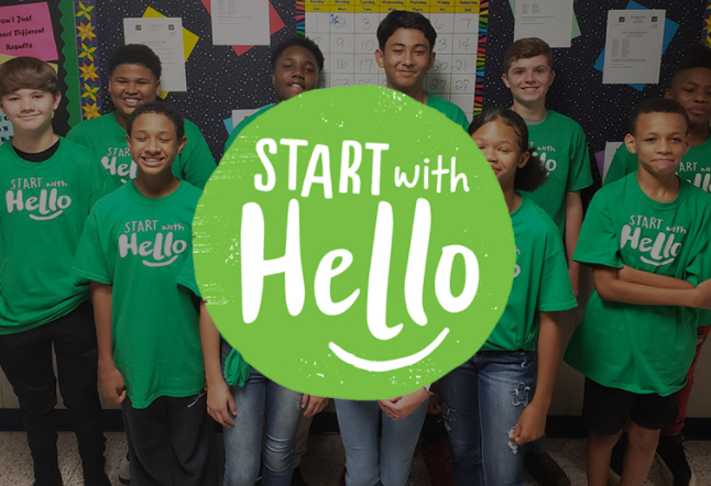 Children holding a sign that says Start with Hello