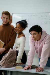 three high school students standing at a desk